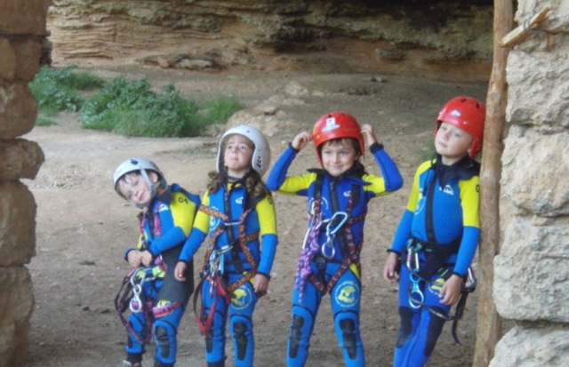ninos con cascos y trajes de neoprenos y arnes